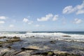 a beautiful spring landscape at Sandy Beach with blue ocean water, silky brown sand, rocks covered in green algae, crashing waves Royalty Free Stock Photo