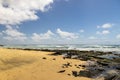 a beautiful spring landscape at Sandy Beach with blue ocean water, silky brown sand, rocks covered in green algae, crashing waves Royalty Free Stock Photo