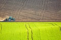 Beautiful spring landscape with working tractor on green and brown field in South Moravia, Czech Republic. Agriculture concept. Royalty Free Stock Photo