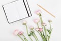 Beautiful spring Ranunculus flowers and empty notebook on white desk from above. Mockup. Pastel color. Clean space for text.