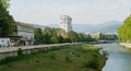 Beautiful spring view of Sochi river, embankment with trees and peaks of the Main Caucasian ridge. People with dogs walk