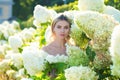 Beautiful spring woman. Sensual girl in blooming bush of hydrangea flowers in spring garden. Hydrangeas shrubs flowers