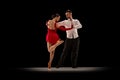 Beautiful stage costumes. Classical performance. Young man and woman dancing tango, ballroom over black background