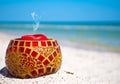 Glass candlestick and a red candle on the sand on a background of blue sea and blue sky Royalty Free Stock Photo