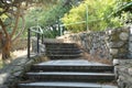 A beautiful staircase with stone steps and a metal lattice among the thickets of trees in a shady Park, the sun shines through the Royalty Free Stock Photo