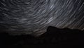 Beautiful star trails time-lapse over the hills. Polar North Star at the center of rotation.
