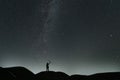 Beautiful starry night, hikers silhouette stands on hill and looks at the Milky Way galaxy.