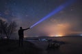 Beautiful starry sky with bright milky way galaxy. Night landscape . Person silhouette stands on the shore with flashlight illumin