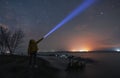 Beautiful starry sky with bright milky way galaxy. Night landscape . Person silhouette stands on the shore with flashlight illumin