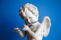 Statue of an angel playing the flute on a blue background portrait Royalty Free Stock Photo