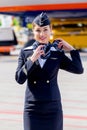 Beautiful stewardess dressed in official dark blue uniform of Aeroflot Airlines on airfield. Passenger jet aircraft on background.