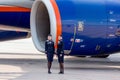 Beautiful stewardesses dressed in official dark blue uniform of Aeroflot Airlines stand near at Rolls Royce`s jet engine