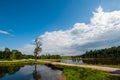 Beautiful still lake with trees on the horizon and white puffy clouds in the sky. Peaceful summer day at the cottage. Large green Royalty Free Stock Photo