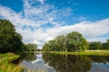 Beautiful still lake with trees on the horizon and white puffy clouds in the sky. Peaceful summer day at the cottage. Large green Royalty Free Stock Photo