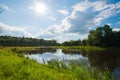 Beautiful still lake with trees on the horizon and white puffy clouds in the sky. Peaceful summer day at the cottage. Large green Royalty Free Stock Photo