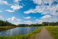 Beautiful still lake with trees on the horizon and white puffy clouds in the sky. Peaceful summer day at the cottage. Large green Royalty Free Stock Photo