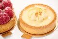 Still life composition with French baked tartlet with lemon meringue and partial view of raspberry cake, isolated white