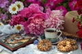 Beautiful still life with peony flowers, cup, cookies and book in the garden. Royalty Free Stock Photo