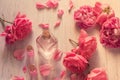 Beautiful still life with rose water in glass bottles and rose flowers on wooden table background, top view