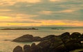 Beautiful stone beach in the morning with golden sunrise sky. Fisherman in long tail boat with folk fishing culture. Peaceful and Royalty Free Stock Photo