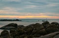 Beautiful stone beach in the morning with golden sunrise sky. Fisherman in long tail boat with folk fishing culture. Peaceful and Royalty Free Stock Photo