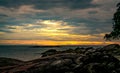 Beautiful stone beach in the morning with golden sunrise sky. Peaceful and tranquil scene. Landscape of calm sea in the morning. Royalty Free Stock Photo