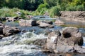 Beautiful stone rapids on the way of a fast flow of a small forest stream on a sunny summer day Royalty Free Stock Photo