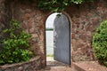 In the beautiful stone wall the iron door is ajar
