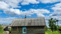 A beautiful stork bird with a red beak sits on a chimney of a wooden house in a village against