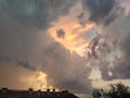 Beautiful storm clouds during sunset over the rooftops. Cumulus clouds illuminated in orange and pink. Delicate pastel tones of Royalty Free Stock Photo