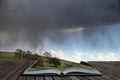 Beautiful stormy moody cloudy sky over English countryside landscape at dusk coming out of pages of open story book Royalty Free Stock Photo