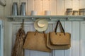 Beautiful straw hats in retro style and vintage woven handbags hang on wooden house wall