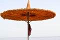 Beautiful straw natural sun umbrellas in the form of hats with clothes and green palm trees in a tropical desert resort against th Royalty Free Stock Photo