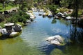 A beautiful stream lined with rocks, plants and trees with a stone lantern at the Japanese Friendship Garden in Balboa Park