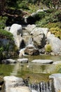 Beautiful stream with small rocky waterfalls lined with rocks, plants and trees at the Japanese Friendship Garden Royalty Free Stock Photo