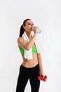 Beautiful strong happy cheerful young sports woman posing indoors drinking water with towel on neck. Royalty Free Stock Photo