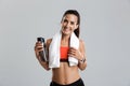 Beautiful strong happy cheerful young sports woman posing isolated indoors drinking water with towel on neck. Royalty Free Stock Photo