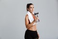 Beautiful strong happy cheerful young sports woman posing isolated indoors drinking water with towel on neck. Royalty Free Stock Photo