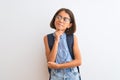 Beautiful student child girl wearing backpack and glasses over isolated white background with hand on chin thinking about Royalty Free Stock Photo