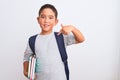 Beautiful student kid boy wearing backpack holding books over isolated white background with surprise face pointing finger to Royalty Free Stock Photo