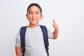 Beautiful student kid boy wearing backpack standing over isolated white background doing happy thumbs up gesture with hand Royalty Free Stock Photo