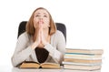 Beautiful student woman sitting and praying with stack of books. Royalty Free Stock Photo