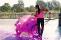 Beautiful stunning girl washes a motorcycle in self service carwash with high pressure foam jet.