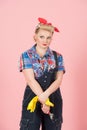 Denim and pin-up styled worker with wrench and yellow gloves. Beautiful styled worker girl isolated in studio on pink background Royalty Free Stock Photo