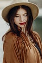 beautiful stylish boho woman with hat, fringe poncho. girl in gypsy hippie look young traveler posing near river rocks in Royalty Free Stock Photo