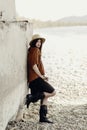 beautiful stylish boho woman with hat, leather bag, fringe poncho and boots. girl in gypsy hippie look young traveler posing near Royalty Free Stock Photo