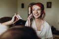 Beautiful stylish bride with red hair talking on phone and smiling, wearing robe,  getting make up done by professional, morning Royalty Free Stock Photo