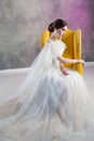 Beautiful and stylish bride in wedding dress in Studio sitting in a chair