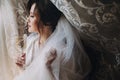 Beautiful stylish brunette bride posing in silk robe under veil with champagne glass in the morning. Happy woman model with Royalty Free Stock Photo