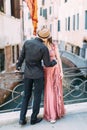 Beautiful stylish couple walking on the bridge of venetian canal in Venice, Italy Royalty Free Stock Photo